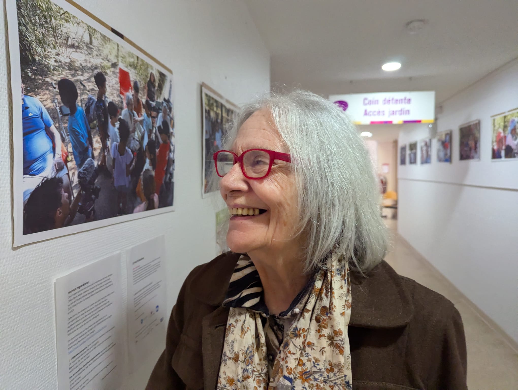 Une femme âgée atteinte de maladie neuro-dégénérative se sourit en se retourvant dans les photos exposées.